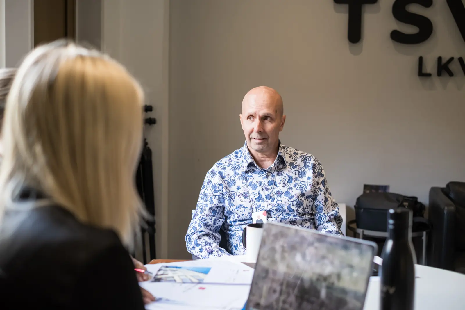 TSVV:n välittäjä keskustelee asiakkaan kanssa toimiston neuvottelupöydän ääressä