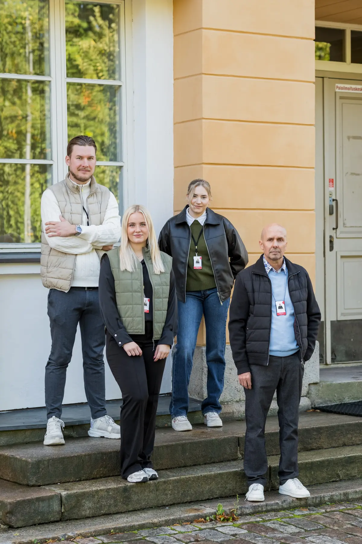 TSVV:n henkilökunta seisoo keltaisen kivitalon edessä